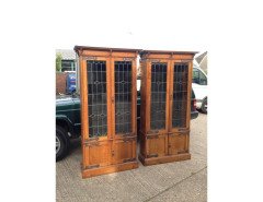 A pair of Arts and Crafts oak glazed bookcases over a lower cupboard - Thumbnail 1