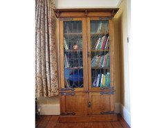 A pair of Arts and Crafts oak glazed bookcases over a lower cupboard - Thumbnail 9